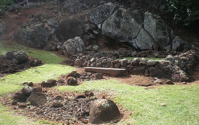 Large gray stones in background with smaller stones and grass  in foreground. 