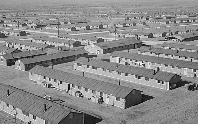 Black and white photo of rows of one-story style barracks. 