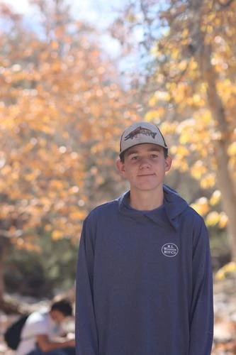 portrait of young man with baseball cap in front of fall foliage