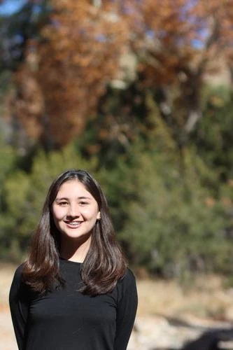 portrait of young woman in front of fall foliage