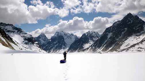 a person skiing across a vast glacier with snowy mountains in the distance