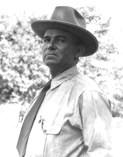 Portrait of Ed Riggs in a shirt and tie, and a brimmed hat