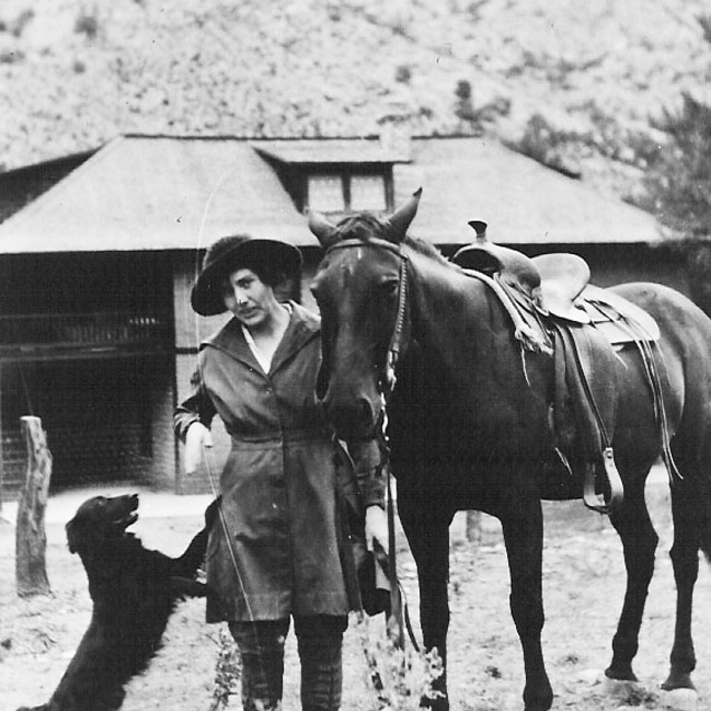 Lillian Erickson Riggs stands between a dog and a horse at Faraway Ranch
