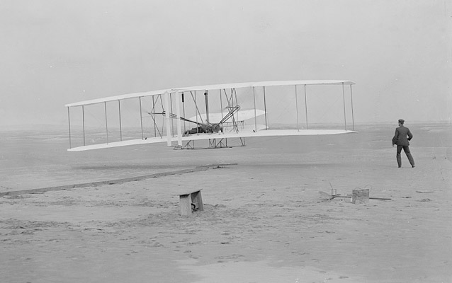The Wright Flyer lifts off with Orville as pilot, Wilbur is running alongside- Kitty Hawk, 1903 