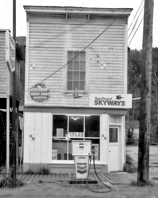 Black and white photo of a building and a gas pump.