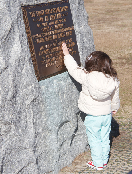 Young girl touching First Flight boulder, 2013