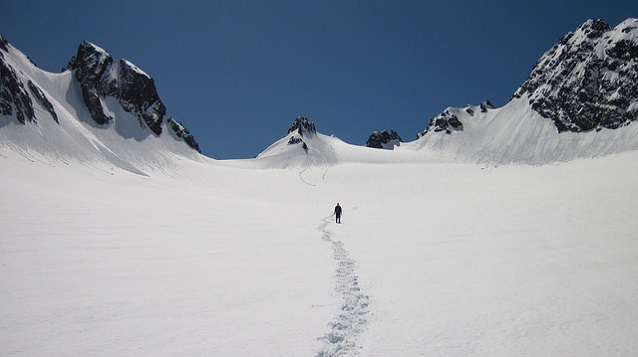 A snowshoer approaches jagged glacial peaks in Olympic National Park (WA)