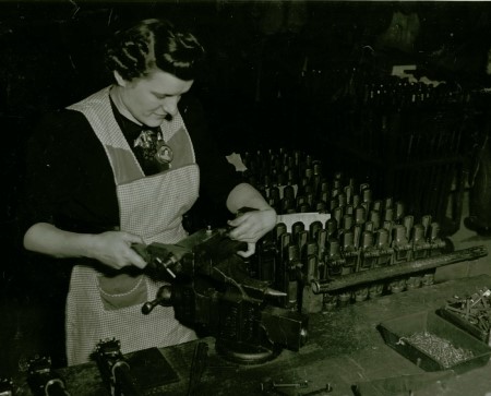 A women wearing an apron works a a machine.