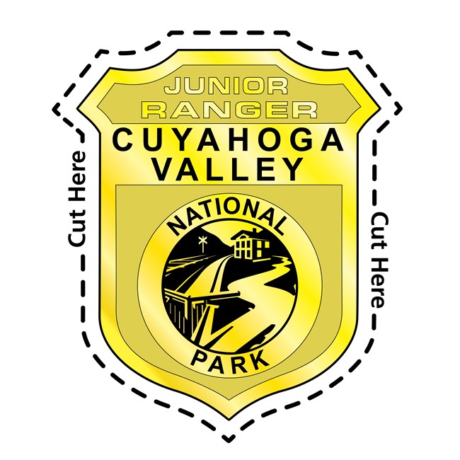 An illustration of the Cuyahoga Valley National Park Junior Ranger Badge, in the shape of a shield, with a dotted "cut here" line traced around it