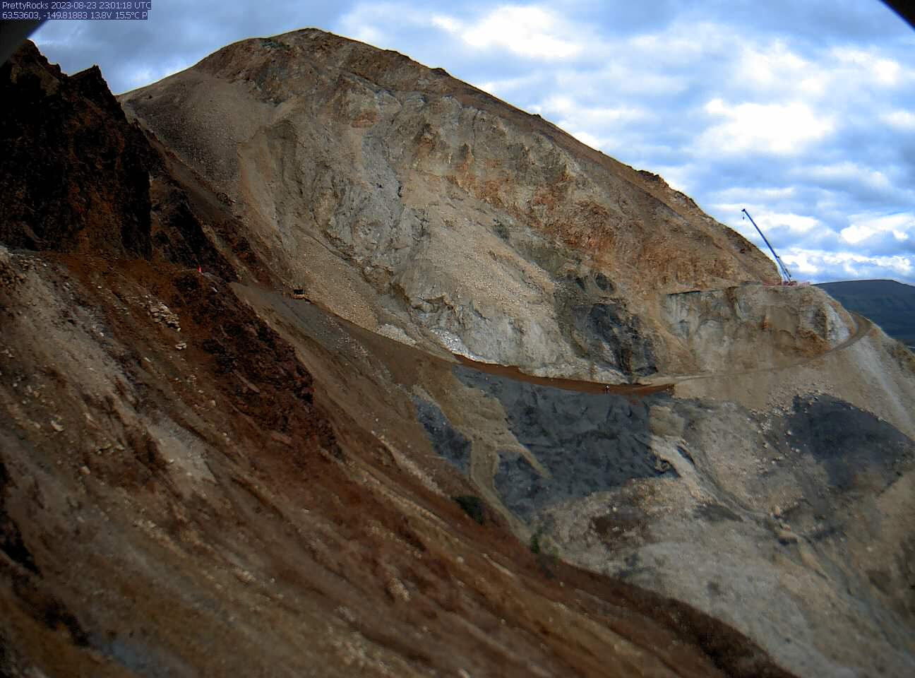 A face-on view of the Pretty Rocks landslide with a steep, sloping bench cut into the mountainside connecting the flat road on each side of the landslide.