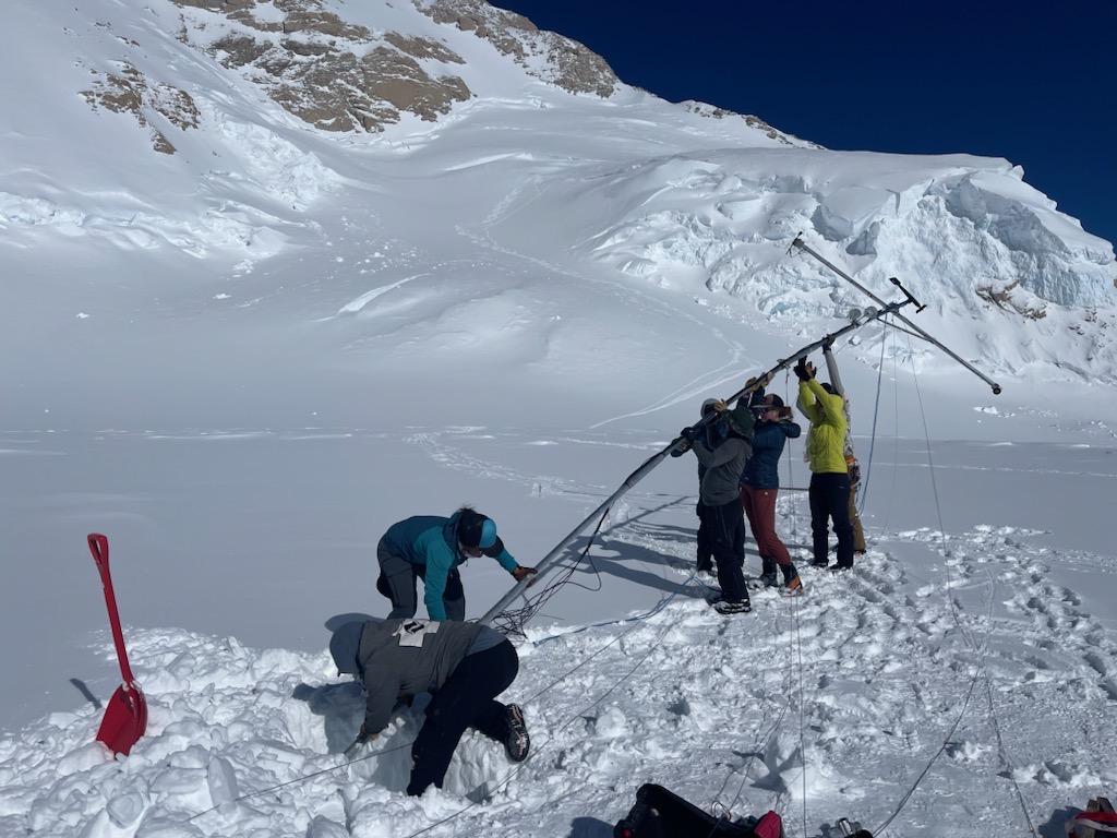 It takes a team of volunteers to raise the long weather station pole 