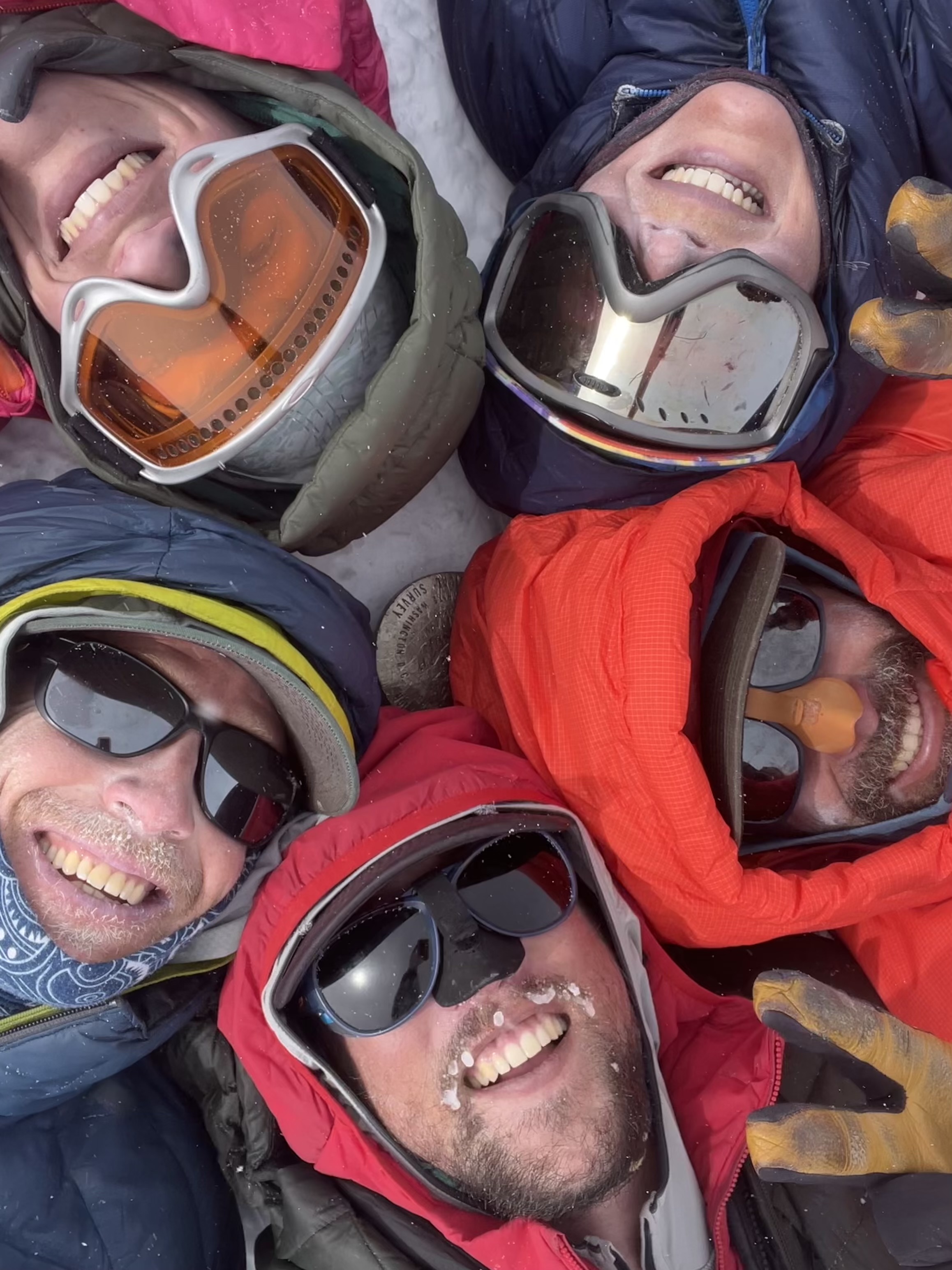 Closeup View from above of five hooded, smiling faces in a circle