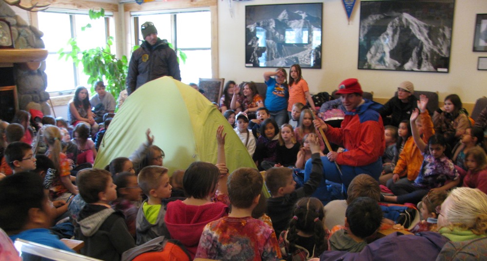 Students surround a tent and two climbers at the Talkeetna Ranger Station