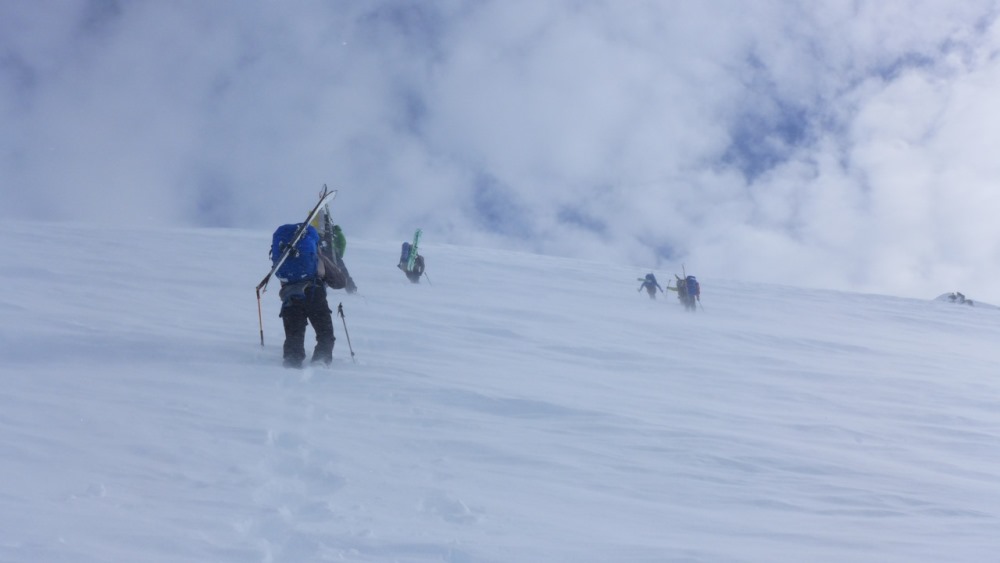 Four climbers ascend a slope in blowing snow