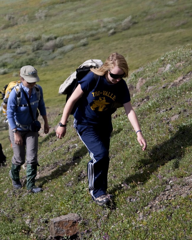 Two students go hiking up a hill in the tundra.