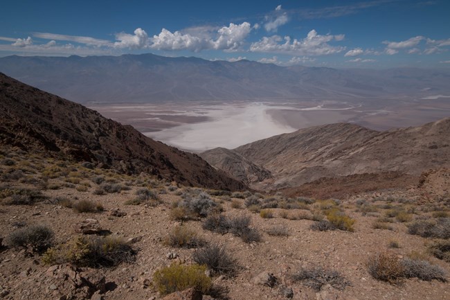 View from a rocky mountain ridge looking down on a vast salt flat.
