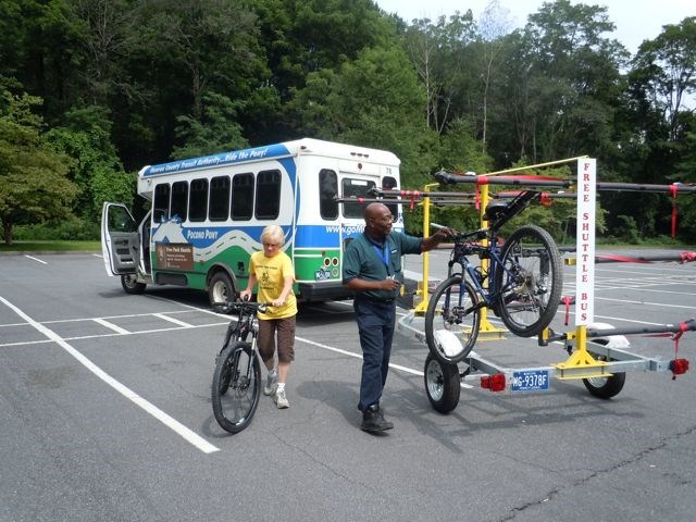 A shuttle driver helping visitors put bikes on the trailer behind the shuttle.