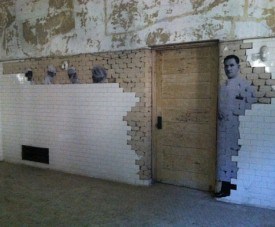 Nurses and doctors seem to appear from behind a tile wall as part of the JR exhibition in the Ellis Island Hospital complex.