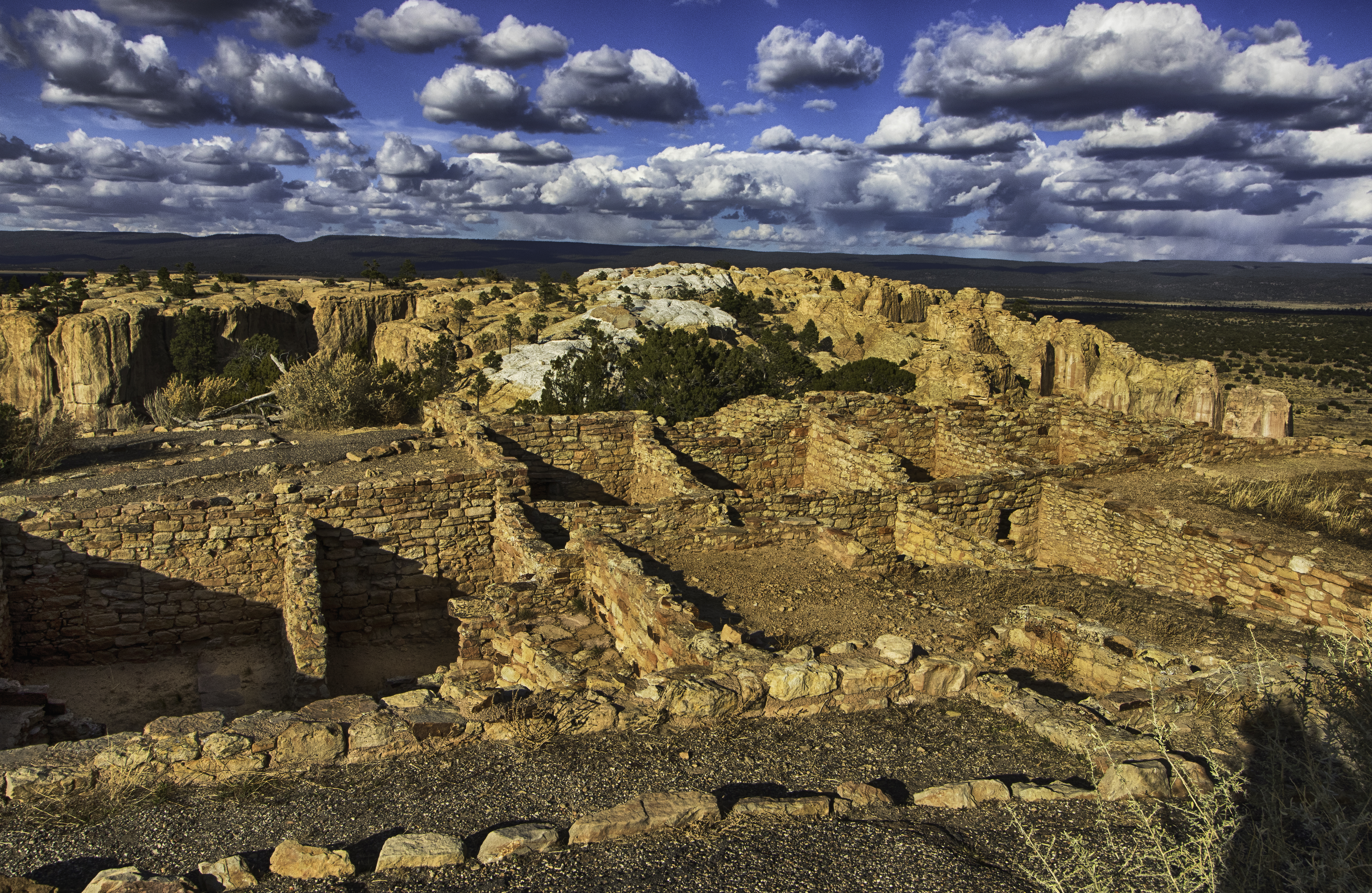 The excavated rooms of a pueblo overlooking a valley