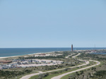 Aerial view of parking lot and winding two-lane roadway, with Robert Moses State Park water tower in background.
