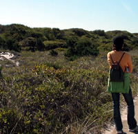 Woman stands on trail with grasses and shrubs nearby. Woman stands on trail with grasses and shrubs nearby.