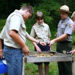 Three boy scouts and a prak ranger screening soil