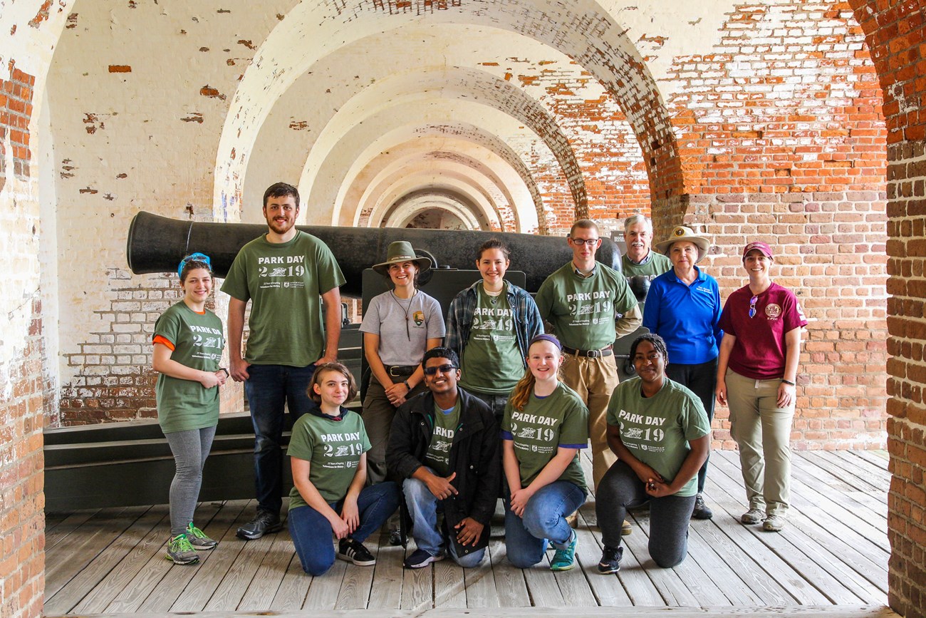 A group of people stand in front of a cannon after volunteering