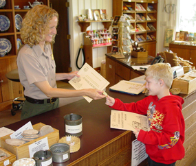 Image of a ranger giving a kid a junior ranger badge and certificate