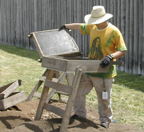Image of a student using a screening device as part of an archaeological excavation at Fort Vancouver.