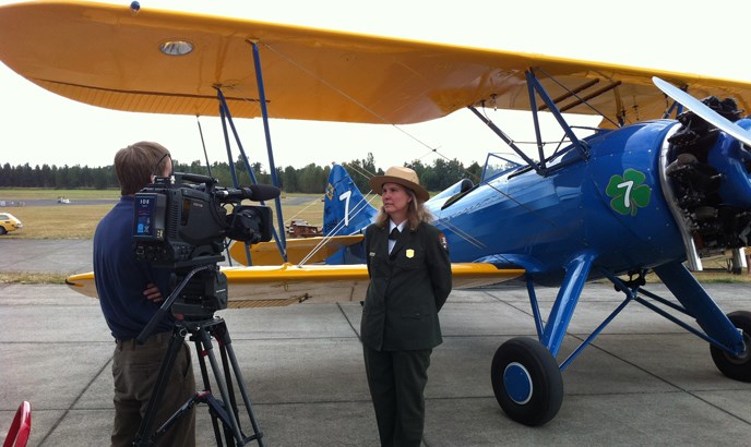 Superintendent Tracy Fortmann speaks to the media in front of a historic biplane at Pearson Air Museum.