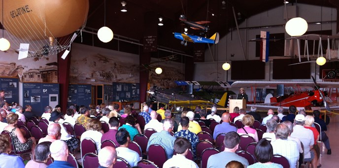 Superintendent Tracy Fortmann speaks to a seated group inside Pearson Air Museum.