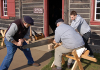 Volunteers work together sawing wood for the Carpenters' Shop