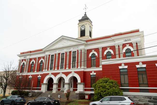 A brick and stone building with a clock tower. Calhoun County Courthouse is written on the building.