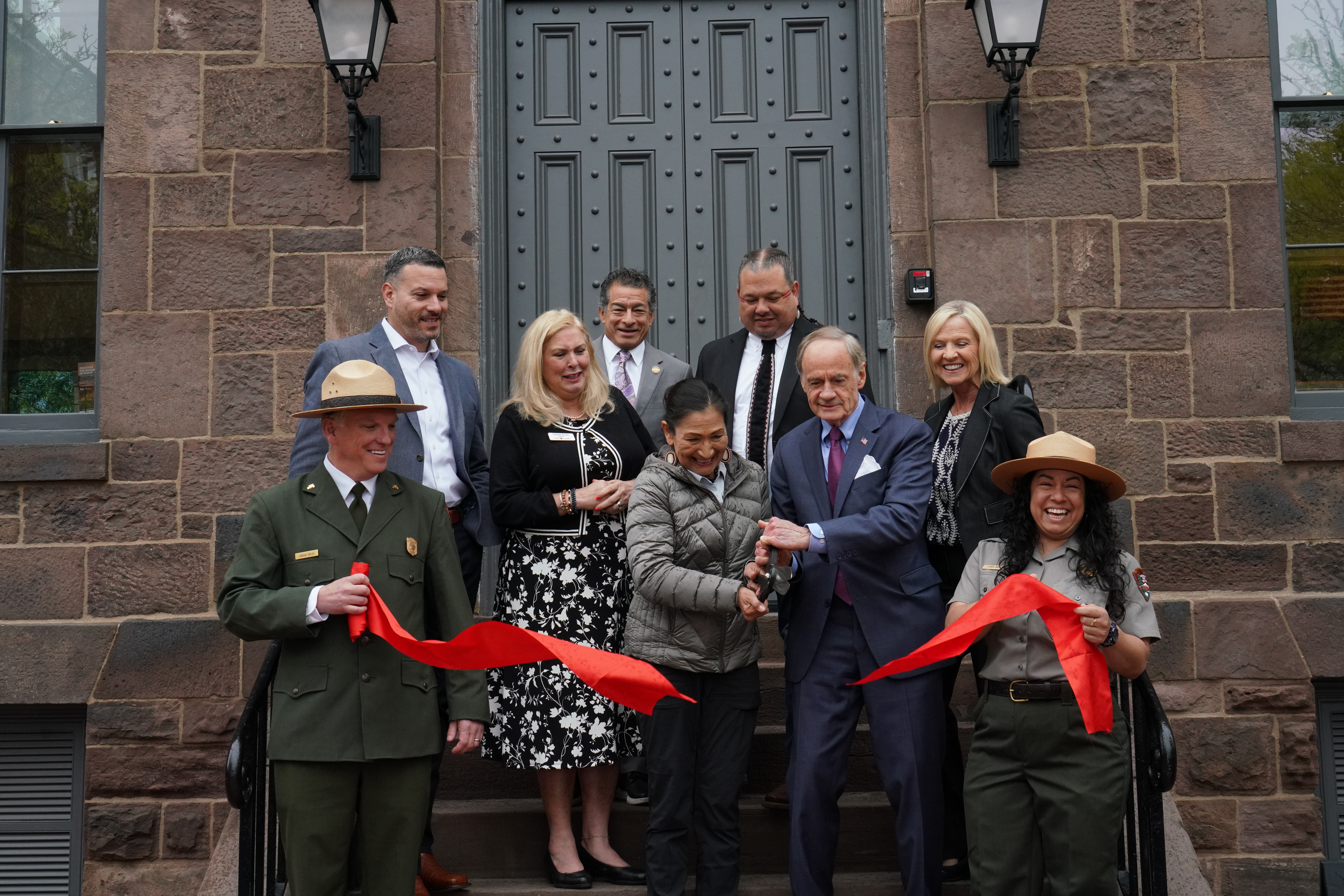 Secretary Deb Haaland and Senator Tom Carper cut a ribbon with Superintendent Joshua Boles, Ranger Lorin Diaz, Lieutenant Governor Bethany Hall-Long, and Mayor Valerie Leary