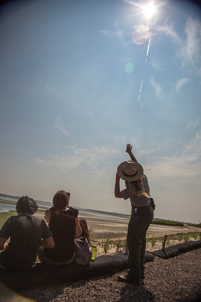 Ranger Erin Schoppmeyer points at the sun during the 2017 solar eclipse at the Jamaica Bay Wildlife Refuge