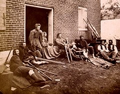 Wounded soldiers sit outside a Civil War hospital.