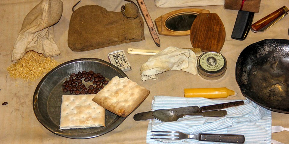 Contents of a traveling trunk include hardtack, beans, rice, eating utensils, plates, and more.