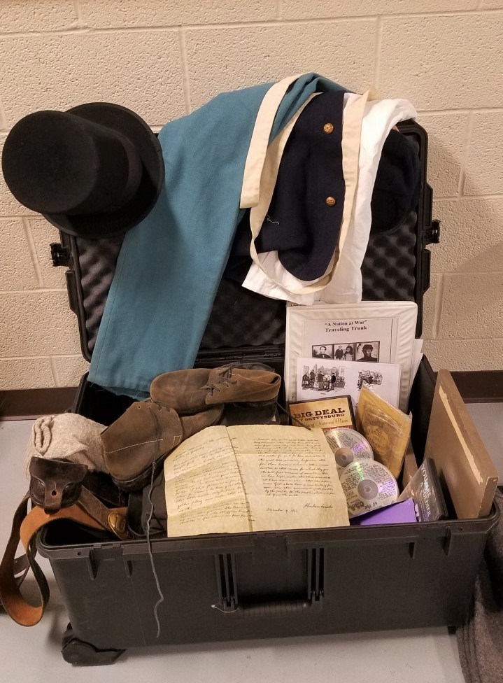 An open Traveling Trunk featuring Civil War era uniforms and items