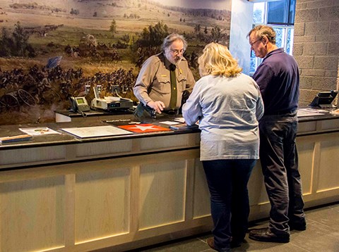Two visitors talk with a park ranger about their visit to the battlefield.