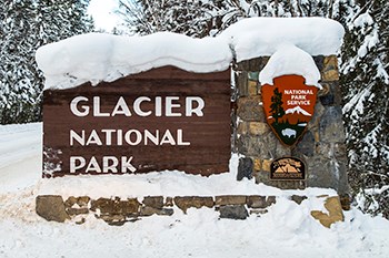 The entrance sign to Glacier National Park in snow
