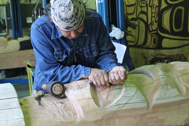 Carver works on a piece of the totem pole