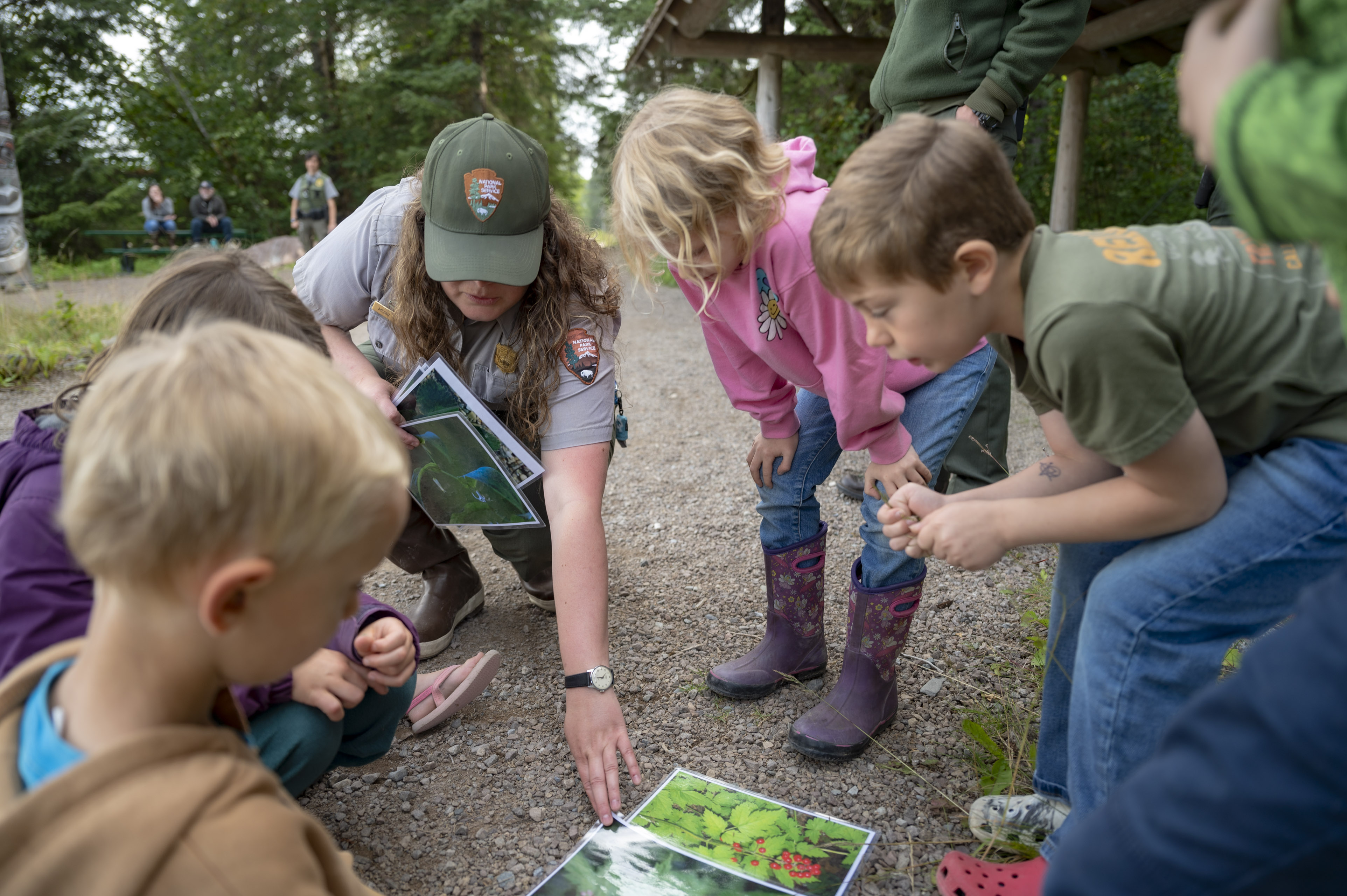 A Park ranger and a group of kids circled around images of berries.