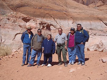 group of people standing in front of sandstone cliff