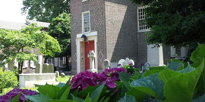 Close-up of a flowering bush. A brick church and burial ground in the background.