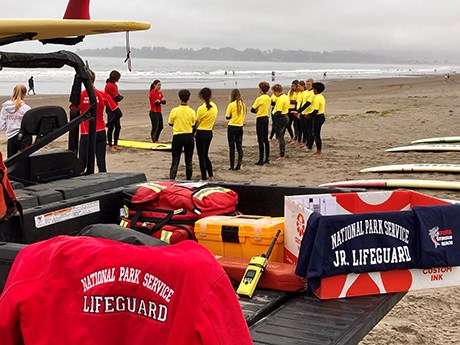 Junior lifeguards receive instruction from lifeguards before a rescue drill at the beach