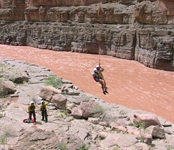 A rafter who had been stranded by flood waters on a ledge above Havasu Creek is lowered to the shore of the Colorado River.