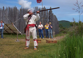 An interpreter in period dress demonstrates loading and firing a flintlock musket. An interpreter in period dress demonstrates loading and firing a flintlock musket.