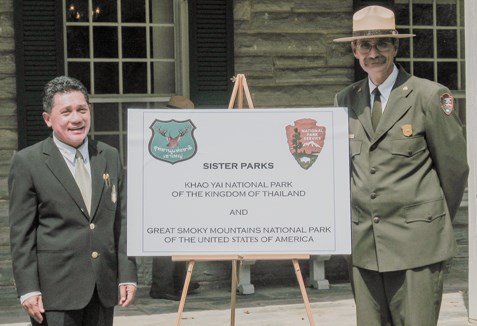 Superintendents of Great Smoky Mountains and Khao Yai National Parks pose for a picture with a sign representing both parks.