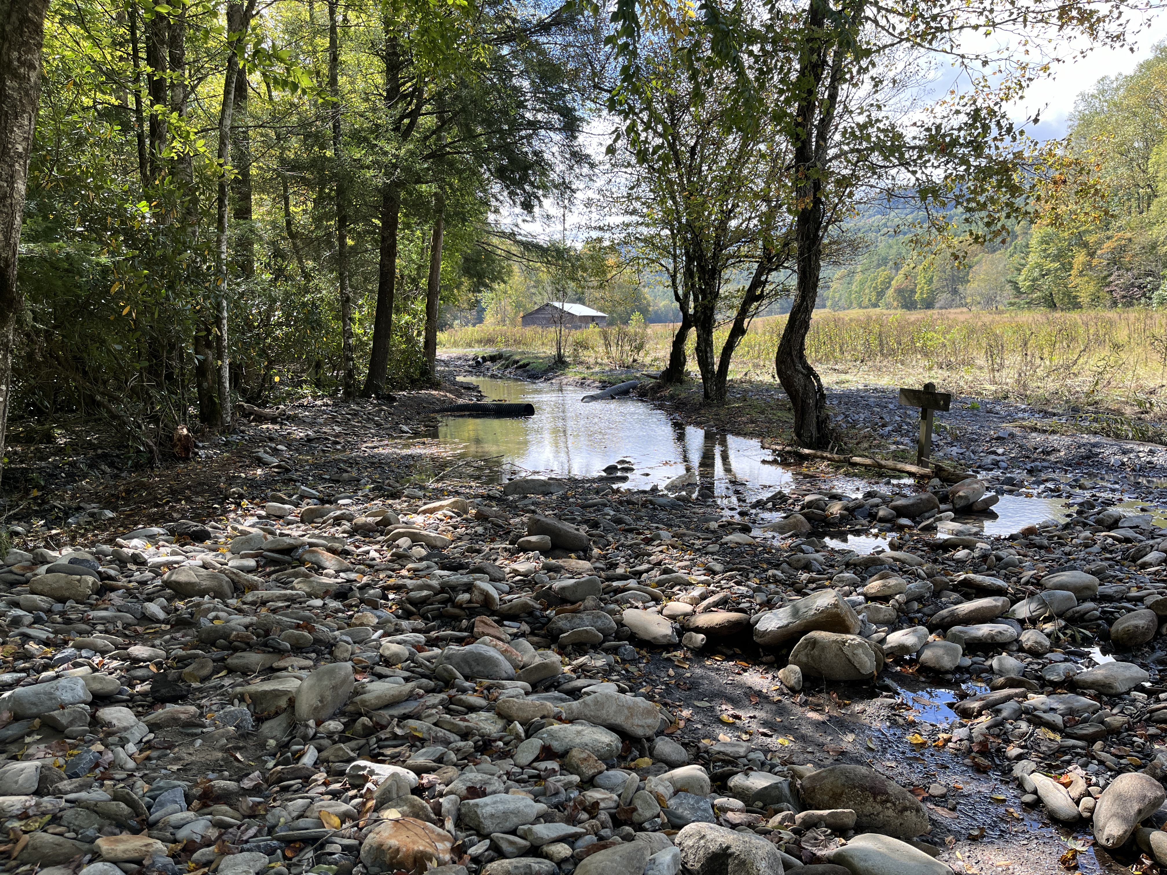 Upper Cataloochee Valley Road sustained significant damage from flooding from Rough Fork Creek and is not drivable. Barn in background.