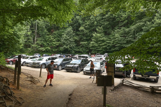 Images of a trailhead with a crowded parking lot in the background.